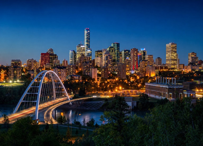 Edmonton city skyline at dusk, with downtown towers lit against a deep blue evening sky