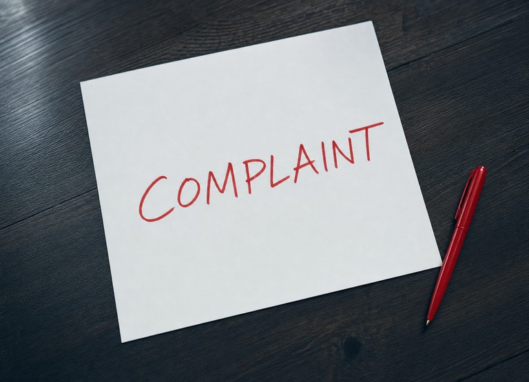 Paper on table with complaint written in red ink.